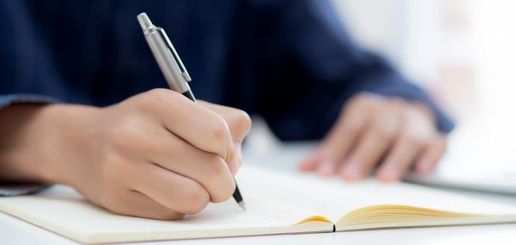 Closeup hand of man writing on notebook with pen on desk, freelance is author, businessman write on notepad on table, book, letter and report, finance and document, business or education concept.