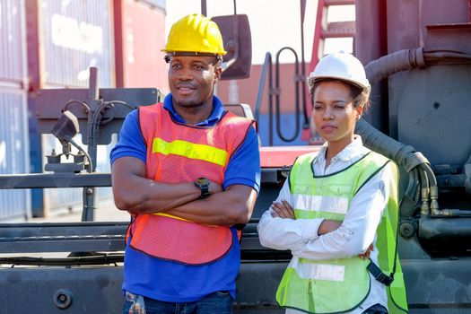 African workers man and woman stand in front of big tractor in cargo shipping area.