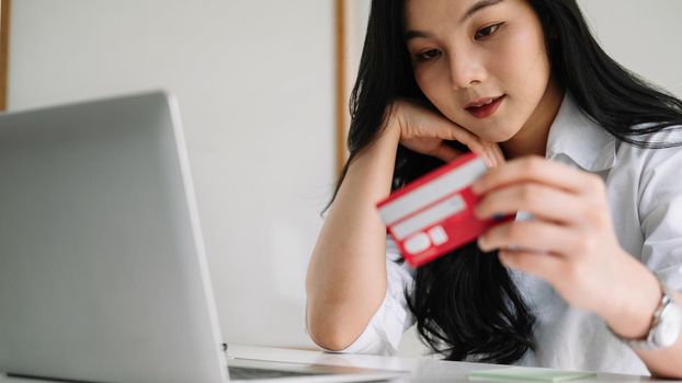 Close up woman using credit card for purchasing and shopping online on laptop computer.