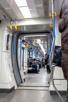 Public transport in the city. Moscow Metro. Yellow handrails for hands close-up. A full subway car lately in the evenings. There are a lot of people in a modern subway car.