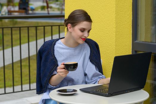 Charming happy woman student using laptop computer to prepare for the course work. Concept of working outdoors