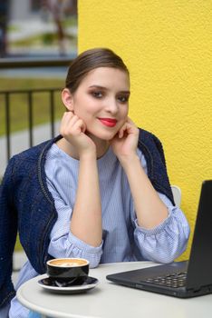 Charming happy woman student using laptop computer to prepare for the course work. Concept of working outdoors