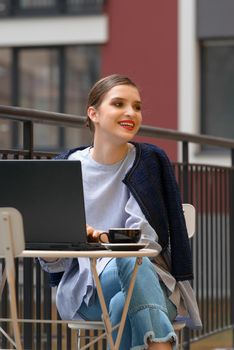 Charming happy woman student using laptop computer to prepare for the course work. Concept of working outdoors