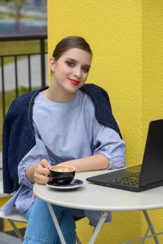 Charming happy woman student using laptop computer to prepare for the course work. Concept of working outdoors