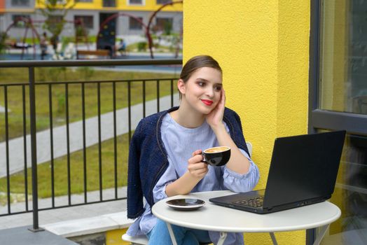 Charming happy woman student using laptop computer to prepare for the course work. Concept of working outdoors