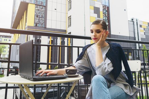 Charming happy woman student using laptop computer to prepare for the course work. Concept of working outdoors