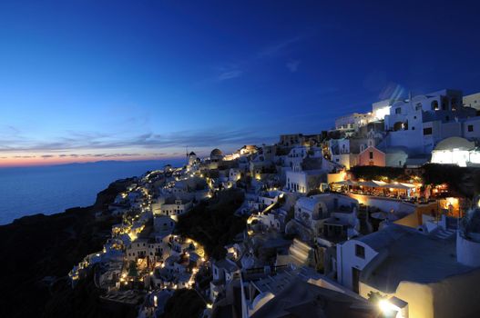 Sunset night view of traditional Greek village Oia on Santorini island in Greece. Santorini is iconic travel destination in Greece, famous of its sunsets and traditional white architecture