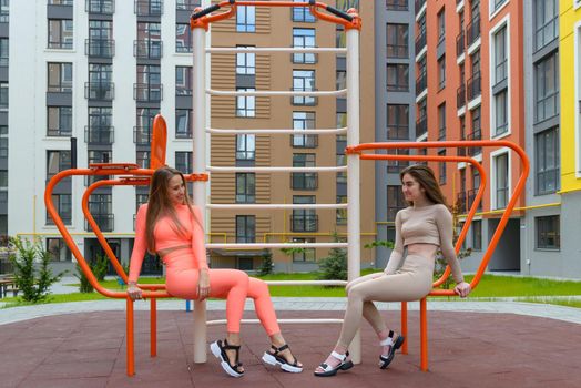 Two sporty young sexy women posing on the summer playground. Healthy lifestyle concept.