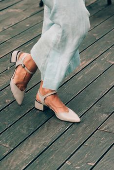 female legs in blue cotton pants and beige shoes. Summer fashion