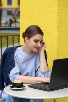 Charming happy woman student using laptop computer to prepare for the course work. Concept of working outdoors