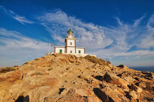 Lighthouse with greek flag in Santorini, cyclades island, with blue sky