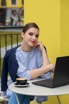 Charming happy woman student using laptop computer to prepare for the course work. Concept of working outdoors