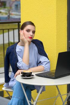 Charming happy woman student using laptop computer to prepare for the course work. Concept of working outdoors