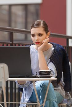 Charming happy woman student using laptop computer to prepare for the course work. Concept of working outdoors