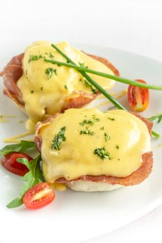 eggs benedict breakfast with ham and hollandaise sauce on white background in modern restaurant