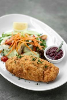 chicken cordon bleu meal with salad and red berry coulis in french restaurant