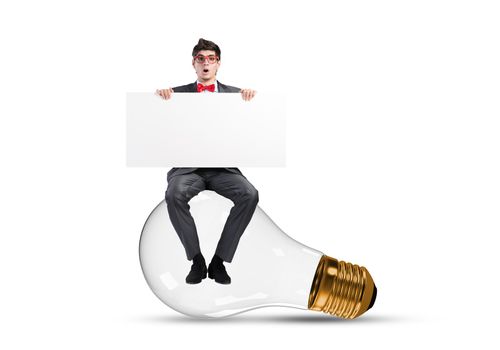 a young businessman sits on a light bulb. with blank banner
