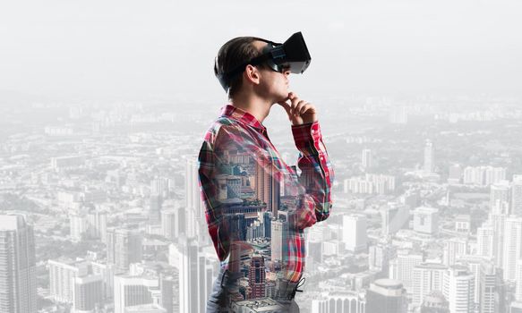 Young man with virtual reality headset or 3d glasses over cityscape background