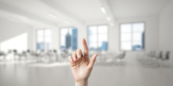 Close of woman hand touching screen with finger and office at background