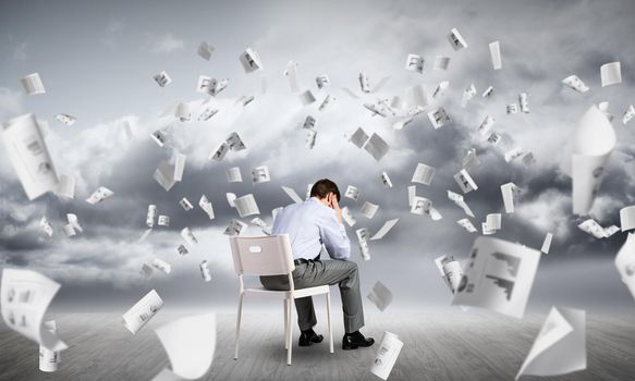 Businessman is sitting on an office chair with his head in his hands. Business stress and problems