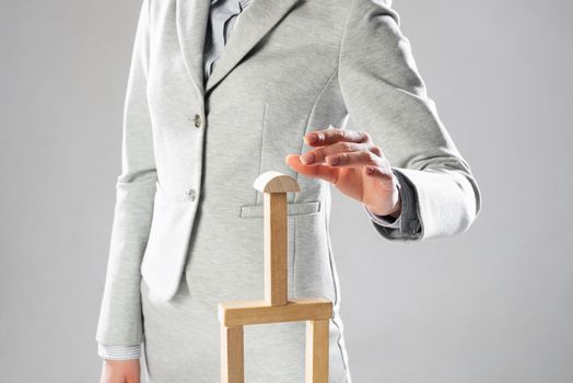 Business woman building construction on table from wooden blocks. Strategy planning and company development. Young woman wearing formal wear sitting in office interior. Business motivation concept