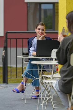 Charming happy woman student using laptop computer to prepare for the course work. Concept of working outdoors