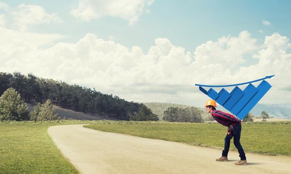 Young man builder carrying growing graph on his back