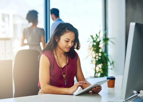 Cropped shot of a young businesswoman working on a digital tablet in a modern office.