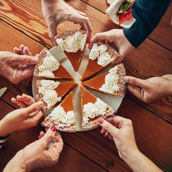 Cropped shot of a group of people each taking a slice of pumpkin pie.