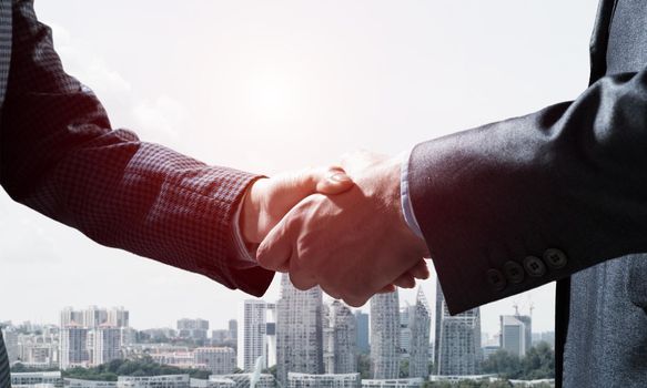 Close-up of the handshake of businessmen. Against the backdrop of the cityscape