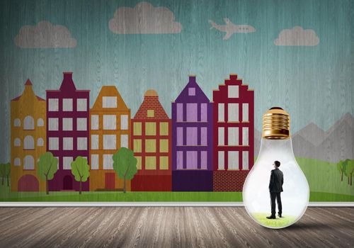 Businessman inside light bulb against city drawn concept