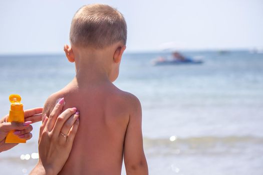 Mother puts cream on her son's back. Caring for baby skin. Sunscreens in the travel. selective focus