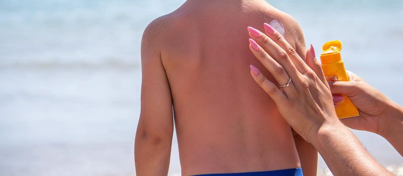 Mother puts cream on her son's back. Caring for baby skin. Sunscreens in the travel. selective focus