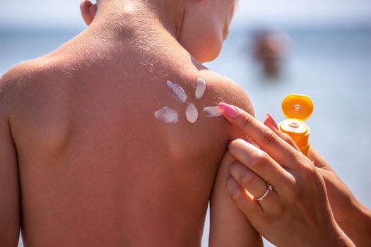 Mother puts cream on her son's back. Caring for baby skin. Sunscreens in the travel. selective focus