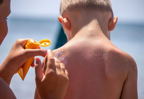 Mother puts cream on her son's back. Caring for baby skin. Sunscreens in the travel. selective focus