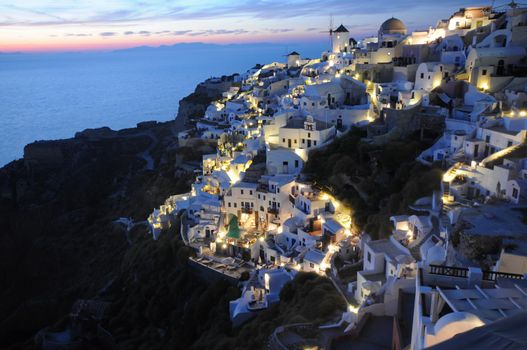 Sunset night view of traditional Greek village Oia on Santorini island in Greece. Santorini is iconic travel destination in Greece, famous of its sunsets and traditional white architecture