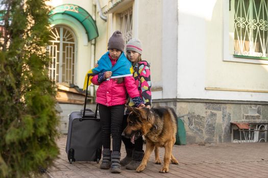 Ukraine military migration. two little girls with a suitcase. Flag of Ukraine, help. Crisis, military conflict.