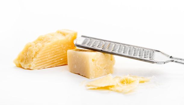 Piece of parmesan cheese and grater on white background