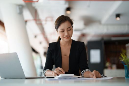 Happy asian businesswoman working for financial marketing with calculator at modern office.