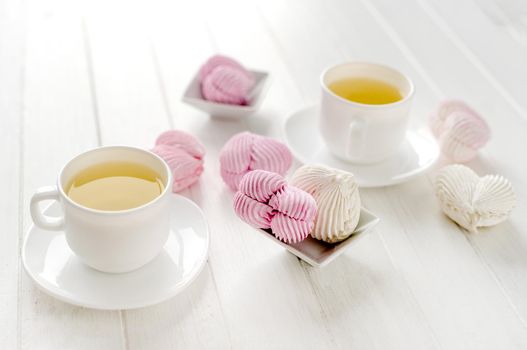 Heart shape marshmallows and cups with tea on table closeup. Craft desert sweets with beverage romantic composition for Valentine day