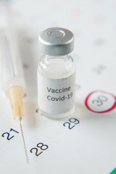 coronavirus vaccine, syringe and calendar on table .