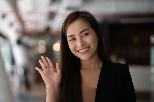 Smiling asian woman waving hand looking at camera, she making video blog or call at home, happy friendly vlogger
