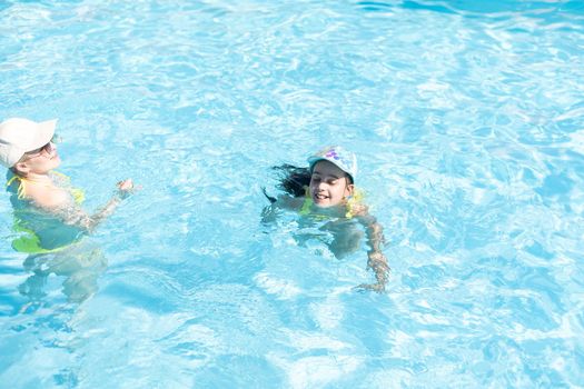 Beautiful woman with her daughter in swimming pool.
