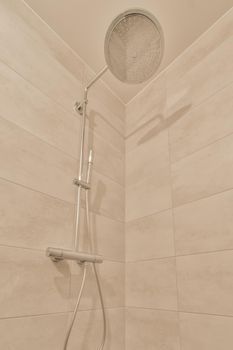 The bathroom is surrounded by marble tiles with shower in the modern house