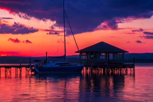 Exciting long exposure landscape on a lake with Yacht and wooden small house in the water