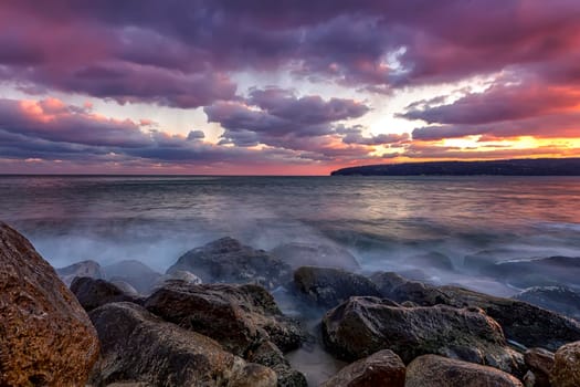 Amazing view after sunset at the rocky shore with motion blur water