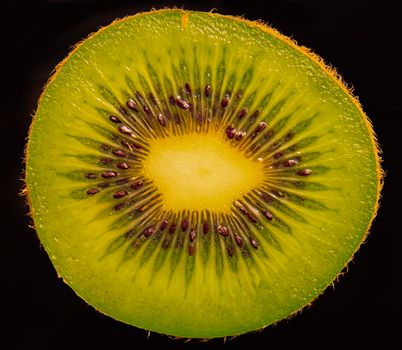 Close up of cutting in half of Kiwi fruit shoot against a black background.