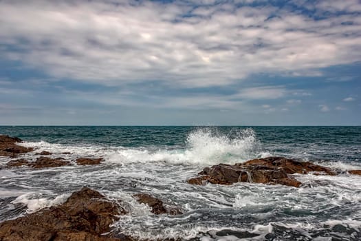 The stunning seascape with the cloudy sky and sea waves at the rocky coastline of the Black Sea