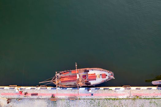 Aerial top view by Drone of the moored small vintage ship at the quay. Parking