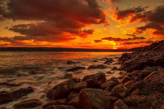 Sunning long exposure sunset over the sea with a rocky beach.